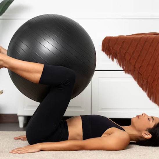 ballon pilates femme pratique ballon entre jambes et lever des jambes